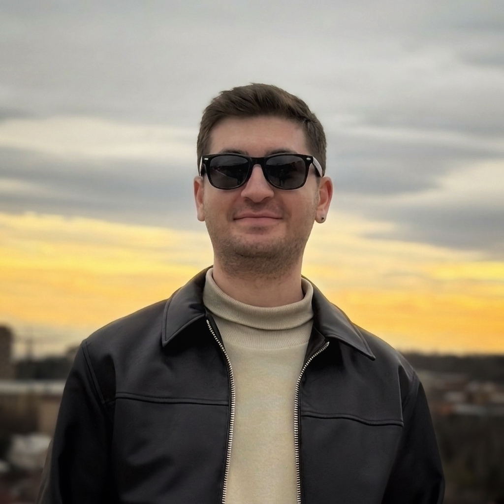 Mohammadreza Amini at dusk, in sunglasses, a cream turtleneck, and a black leather jacket.